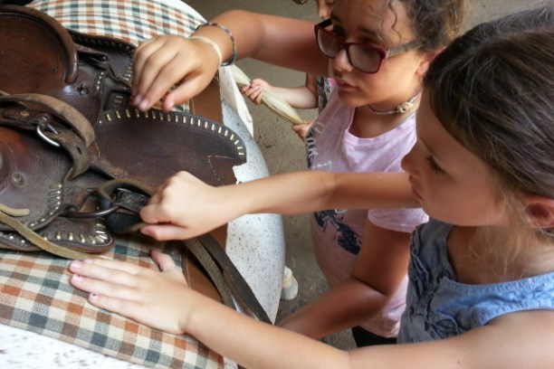 Two girls helping tack up horse