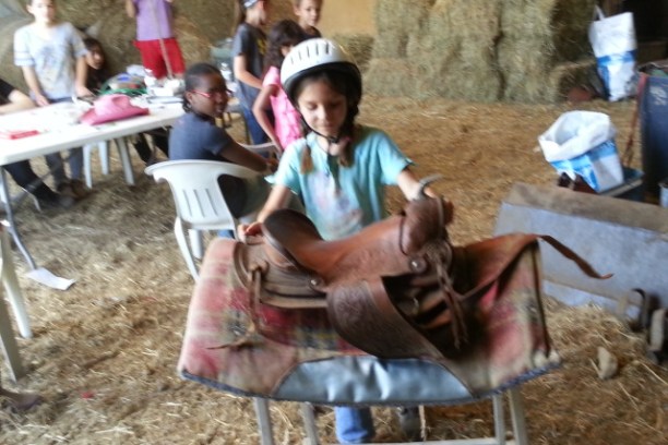Little girl picking up saddle