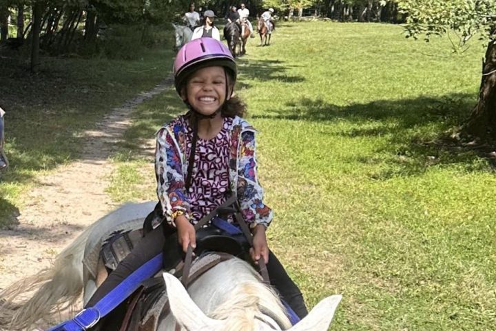 a little girl riding on the back of a horse