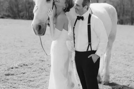 Couple with a white horse in a field, dressed in formal attire.
