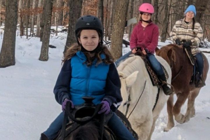 a group of people riding horses on a trail in the snow