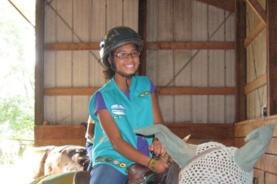 a little girl riding on the back of a cage