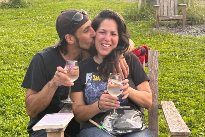 a man and a woman sitting on a bench talking on a cell phone