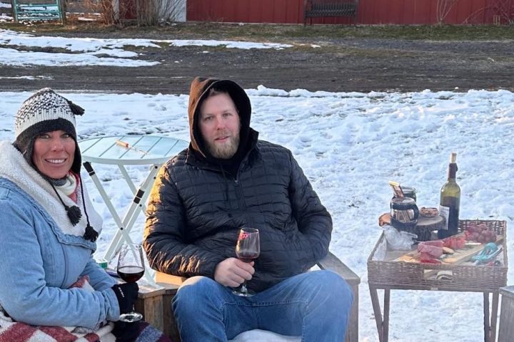 a man and a woman sitting on a bench in the snow