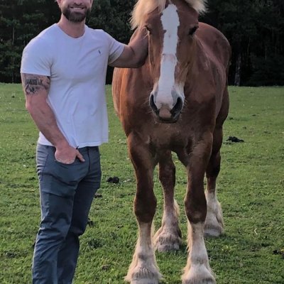 Chris Cope standing next to a horse in a field
